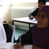 School girl wearing headscarf sitting at her desk in class