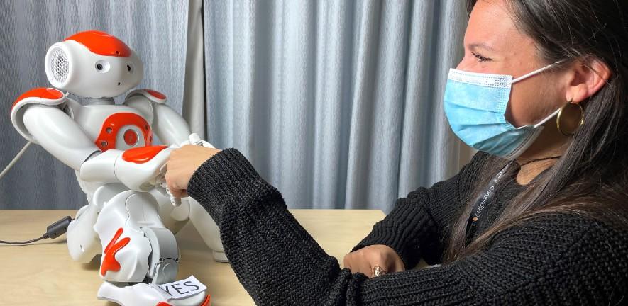 Photo of Micol Spitale shaking hands with Nao the humanoid robot
