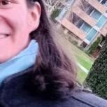 Paul outside in a coat, grinning playfully, the houses in the background and the trees except one next to Paul are at a 45° angle