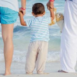 photo of toddler holding parents' hands on the beach